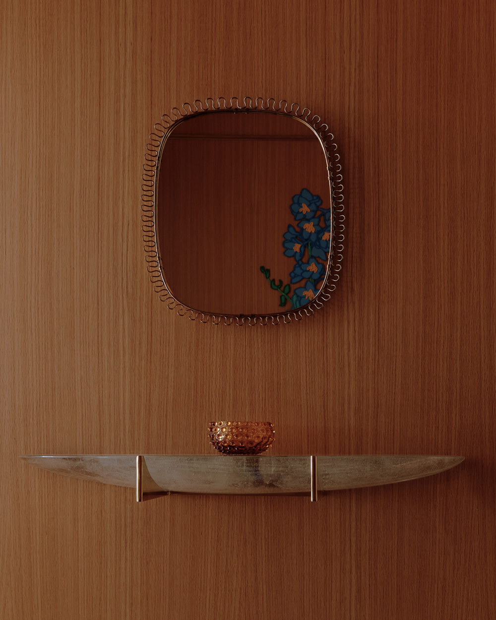 brass and cast-glass floating console under a vintage Josef Frank mirror for Svenskt Tenn on a wood-paneled wall in the elevator vestibule of a duplex apartment on New York's Park Avenue designer by Bryan O'Sullivan