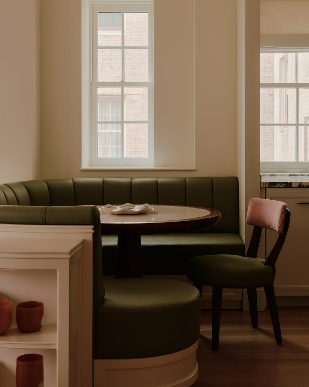 Olive green rounded banquette with round table and single chair in the Kitchen of a duplex apartment on New York's Park Avenue designer by Bryan O'Sullivan