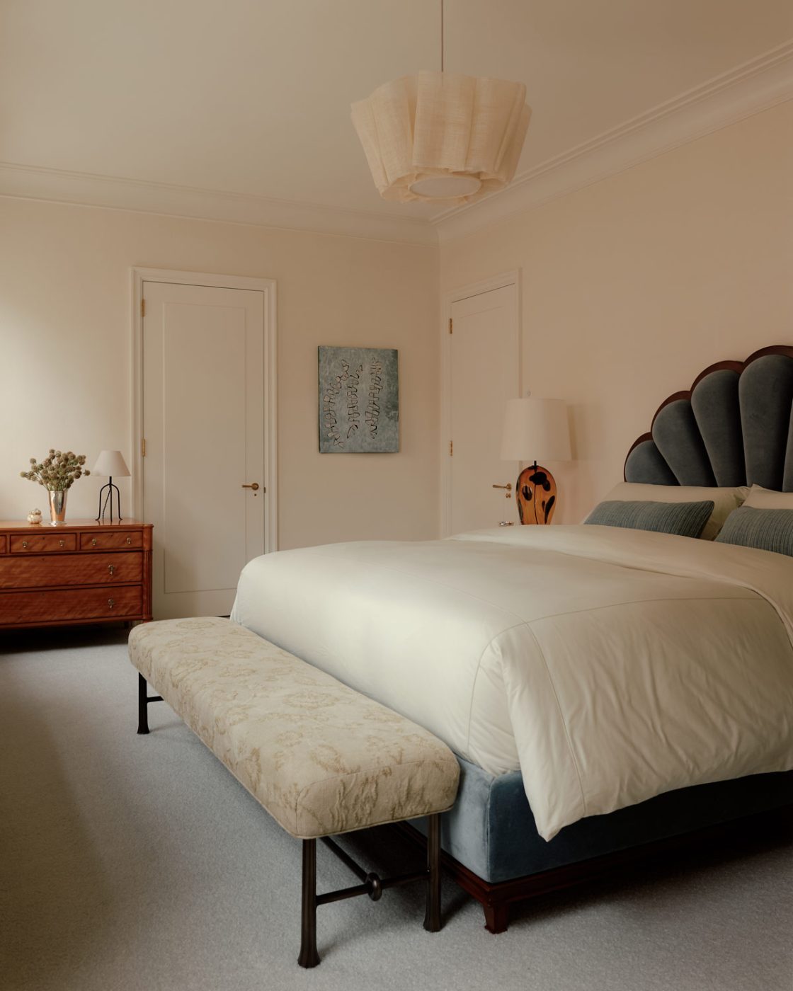 a late-19th-century satinwood English chest of drawers, shell upholstered headboard and foot bench in the primary bedroom of a duplex apartment on New York's Park Avenue designer by Bryan O'Sullivan