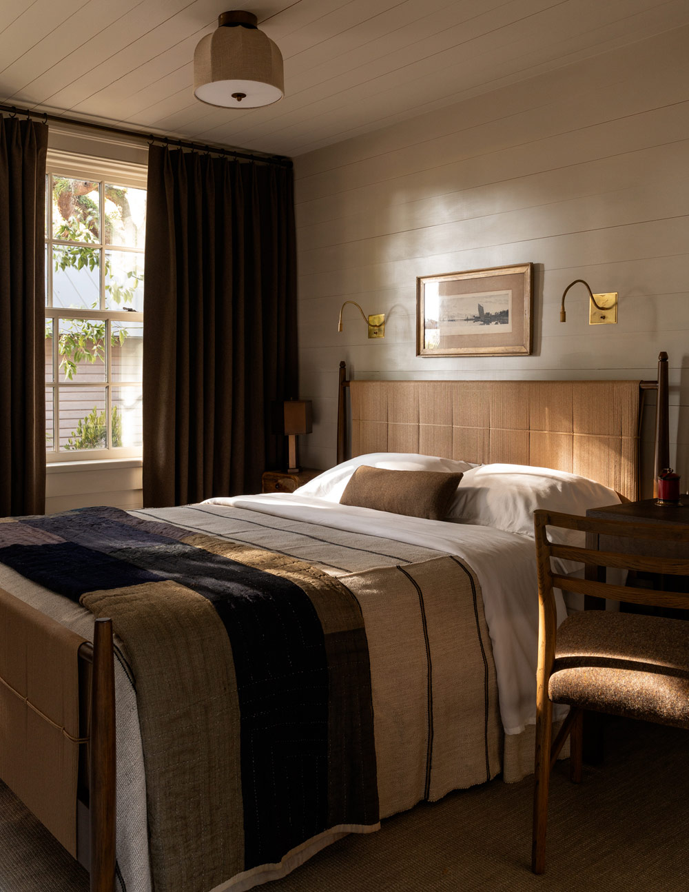 Guest bedroom with woven-rush bed in a former agrarian building on South Carolina's Edisto Island reimagined as a vacation home by interior designer Sean Anderson and architect Will Wingfield