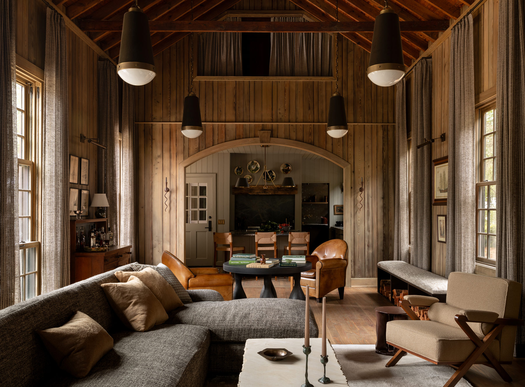 High-ceilinged barn-like beamed great room looking from living area to kitchen in a former agrarian building on South Carolina's Edisto Island reimagined by interior designer Sean Anderson and architect Will Wingfield
