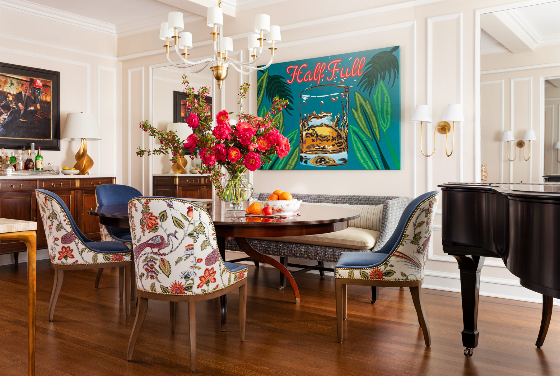 Dining room of Upper East Side New York pied-a-terre designed by Tom Stringer with grand piano, banquette, buffet as bar and brightly colored contemporary art and botanical fabrics on dining chairs, set against largely neutral background